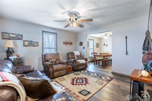 living room featuring a textured ceiling, dark hardwood / wood-style floors, and ceiling fan