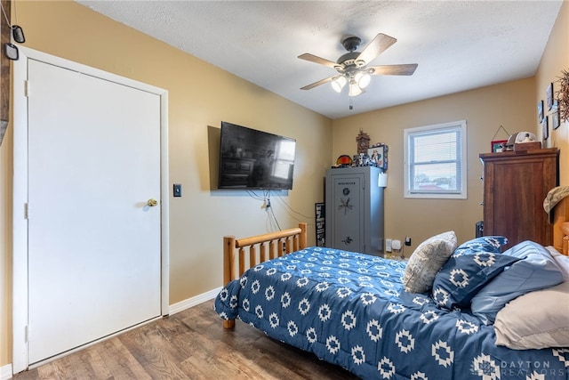 bedroom with ceiling fan, wood-type flooring, and a textured ceiling