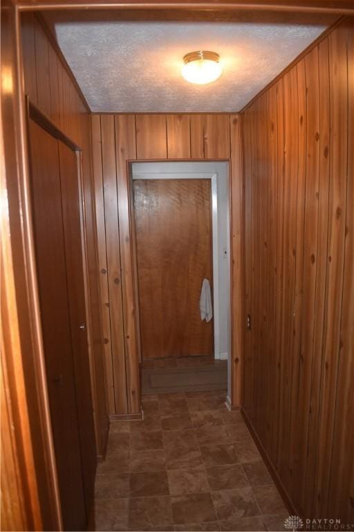 hall with wooden walls and a textured ceiling