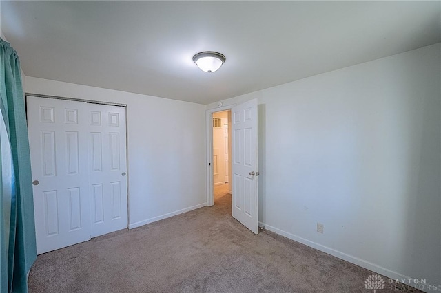 unfurnished bedroom with a closet and light colored carpet