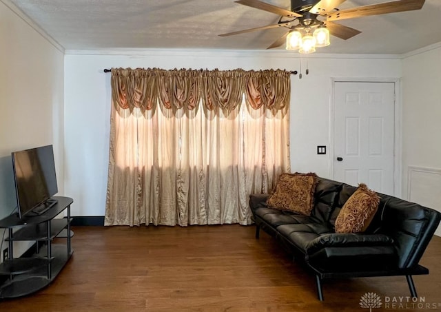 living room with ceiling fan, crown molding, wood-type flooring, and a textured ceiling