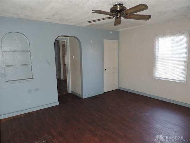 unfurnished room with a textured ceiling, dark hardwood / wood-style flooring, and ceiling fan