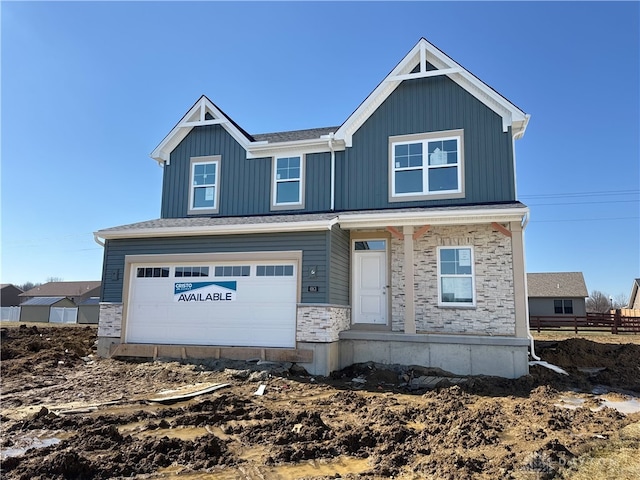 view of front of house with an attached garage, stone siding, and board and batten siding