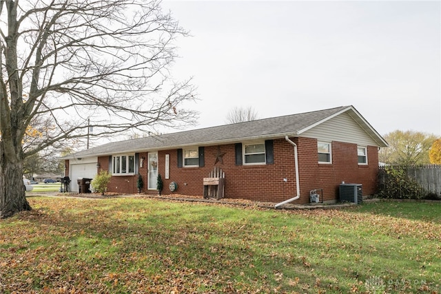 ranch-style home with a front lawn, central AC unit, and a garage