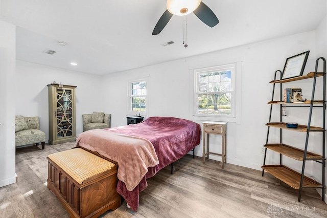 bedroom featuring ceiling fan, light hardwood / wood-style floors, and multiple windows