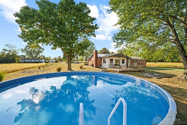 view of swimming pool featuring a lawn and a wooden deck