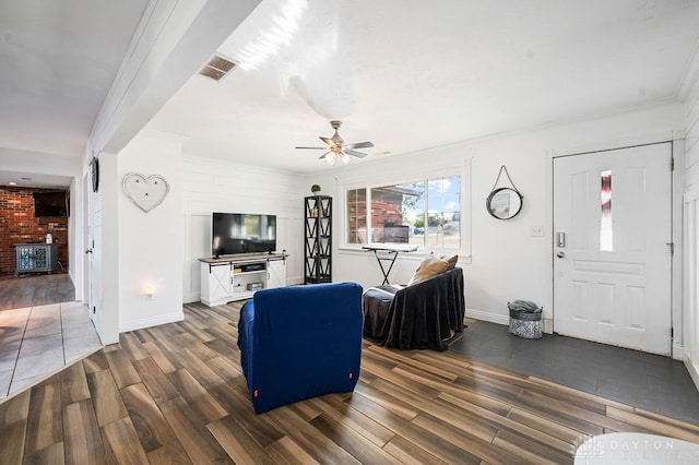 living room with dark hardwood / wood-style flooring, ceiling fan, crown molding, and brick wall