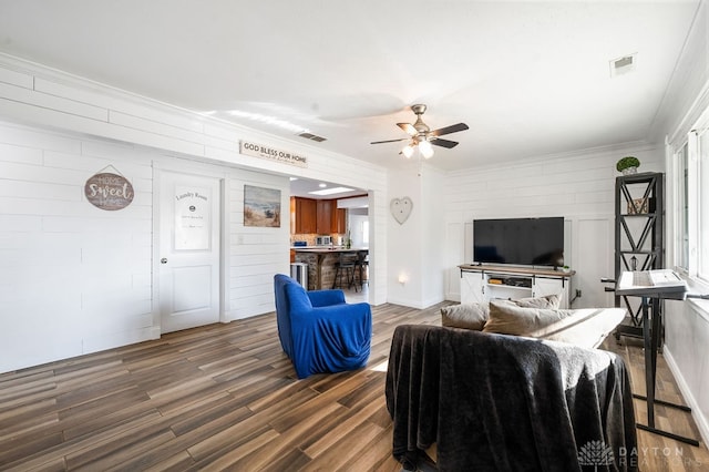 living room featuring dark hardwood / wood-style flooring, ceiling fan, and crown molding