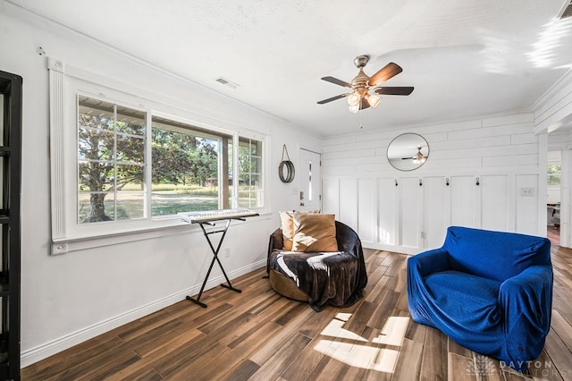 living area with plenty of natural light, dark hardwood / wood-style floors, and crown molding