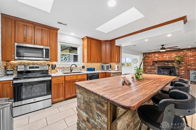 kitchen with a kitchen bar, appliances with stainless steel finishes, ceiling fan, and sink