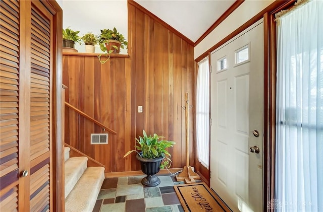 entrance foyer featuring wooden walls and ornamental molding