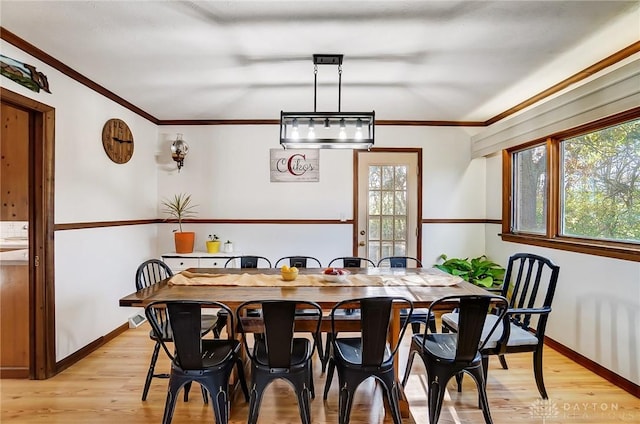 dining space with light hardwood / wood-style floors and ornamental molding