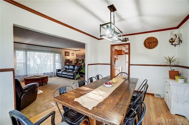 dining room with crown molding and light wood-type flooring