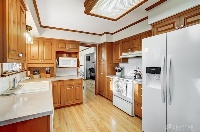 kitchen featuring white appliances, sink, hanging light fixtures, light hardwood / wood-style flooring, and decorative backsplash