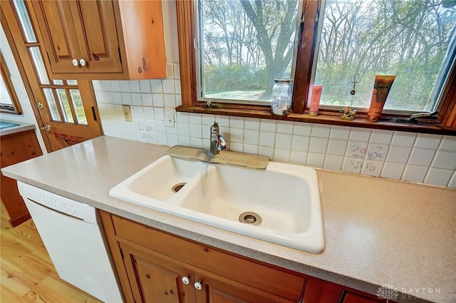 kitchen with sink, white dishwasher, a healthy amount of sunlight, and light hardwood / wood-style floors