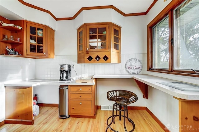 kitchen with decorative backsplash, crown molding, and light hardwood / wood-style floors