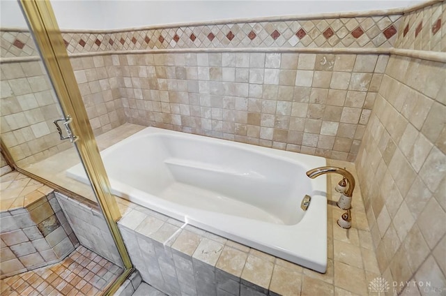 bathroom featuring tile patterned flooring, a relaxing tiled tub, and tile walls