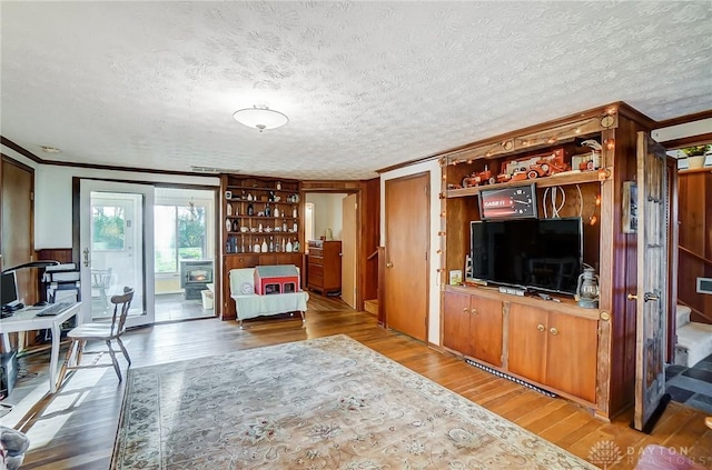 living room featuring crown molding, wood-type flooring, and a textured ceiling