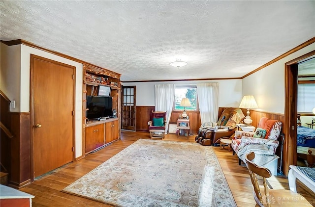 living room featuring crown molding, light hardwood / wood-style flooring, wood walls, and a textured ceiling