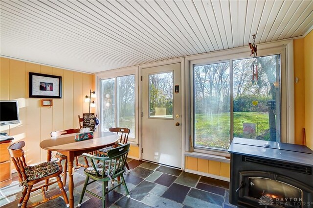 sunroom / solarium featuring a wood stove, plenty of natural light, and wooden ceiling