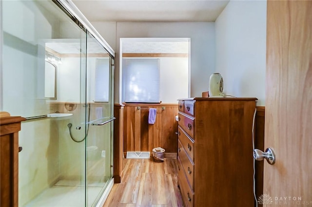 bathroom featuring wood-type flooring and a shower with shower door