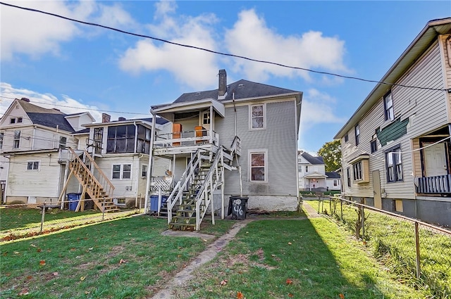 rear view of property featuring a sunroom and a yard