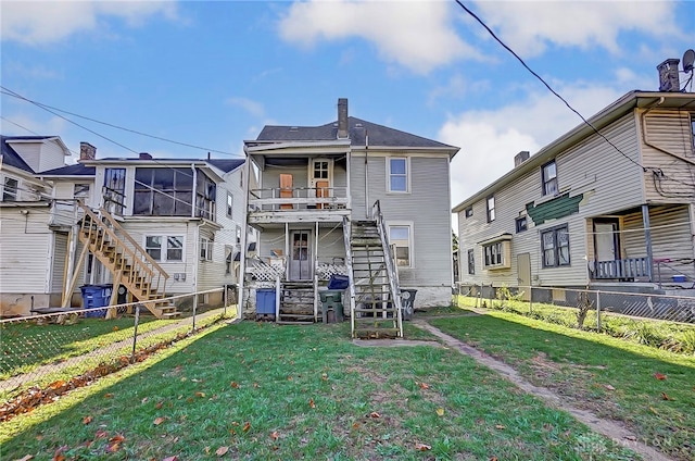 rear view of house featuring a sunroom and a yard