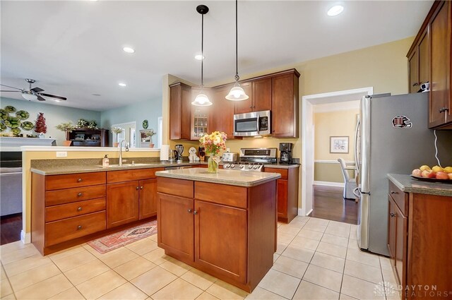 kitchen featuring stainless steel appliances, sink, pendant lighting, light tile patterned floors, and a kitchen island