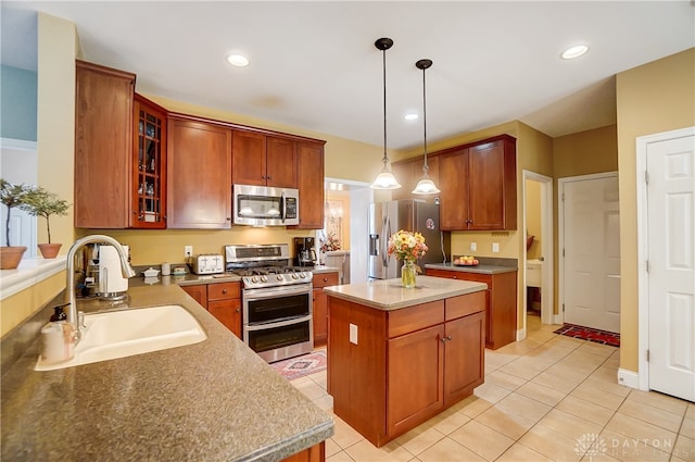 kitchen featuring appliances with stainless steel finishes, sink, light tile patterned floors, decorative light fixtures, and a center island