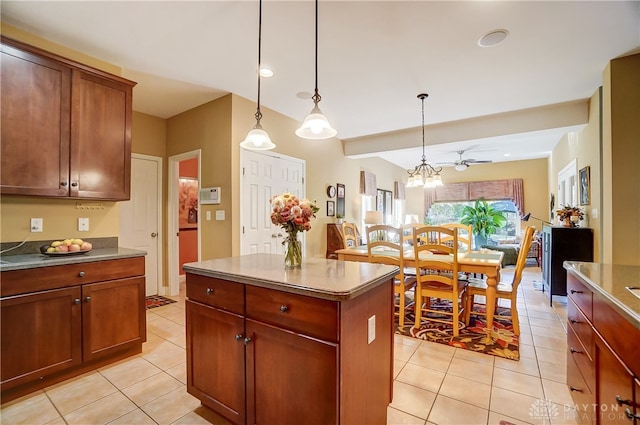 kitchen featuring ceiling fan with notable chandelier, light tile patterned floors, a center island, and hanging light fixtures