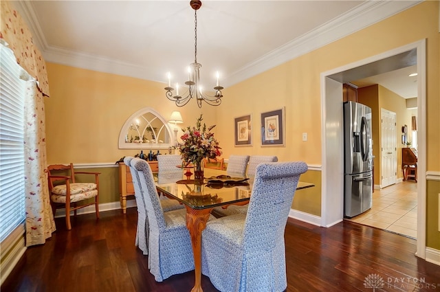 dining space featuring ornamental molding, an inviting chandelier, a healthy amount of sunlight, and hardwood / wood-style flooring