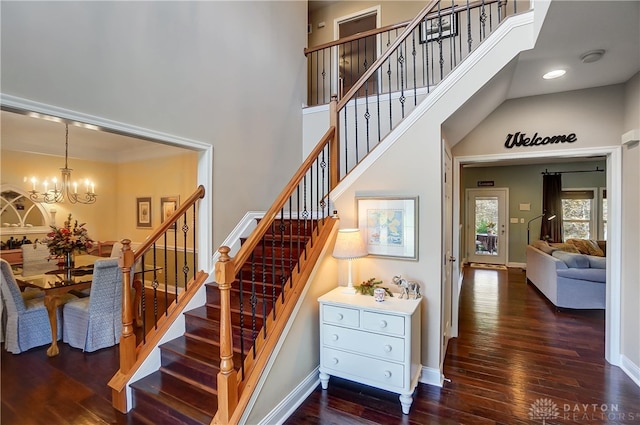 stairs with hardwood / wood-style floors, a towering ceiling, and a chandelier