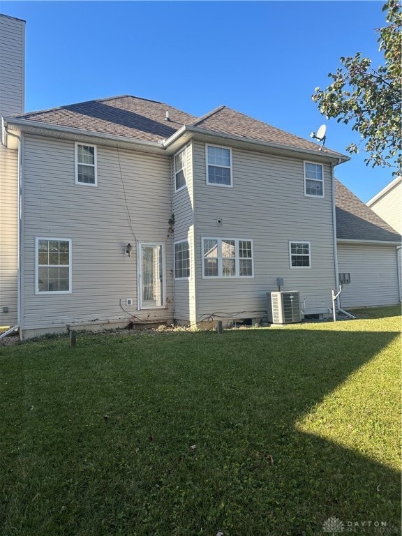 rear view of property with cooling unit and a lawn