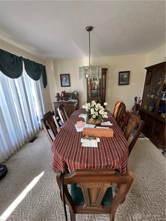 carpeted dining space with an inviting chandelier