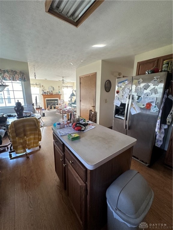 kitchen with stainless steel fridge, dark hardwood / wood-style flooring, a kitchen island, and a textured ceiling