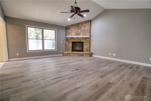 unfurnished living room with lofted ceiling, ceiling fan, light wood-type flooring, a textured ceiling, and a fireplace