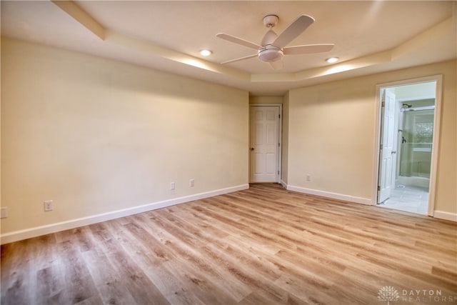 unfurnished room with a tray ceiling, light hardwood / wood-style flooring, and ceiling fan