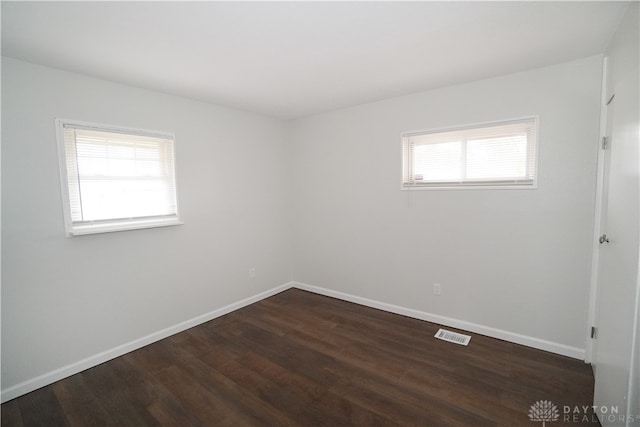 unfurnished room with a healthy amount of sunlight and dark hardwood / wood-style flooring