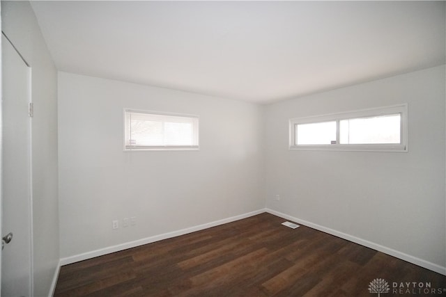 spare room with dark hardwood / wood-style flooring and plenty of natural light