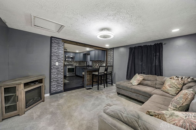 carpeted living room featuring sink and a textured ceiling