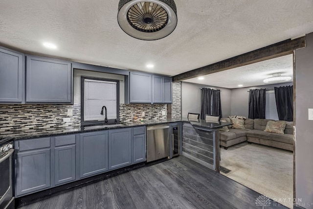 kitchen with sink, dark hardwood / wood-style flooring, a textured ceiling, decorative backsplash, and appliances with stainless steel finishes