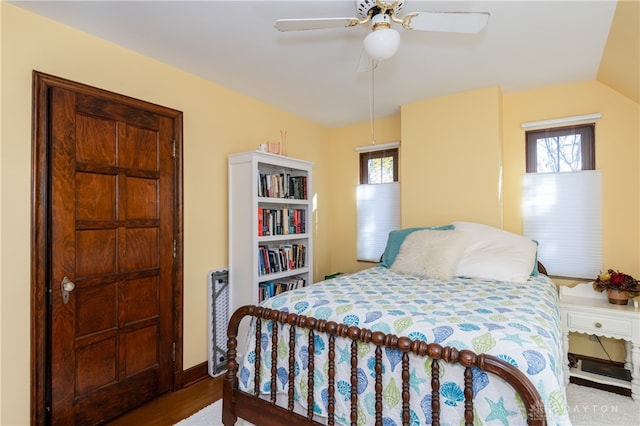 bedroom featuring ceiling fan, vaulted ceiling, wood-type flooring, and multiple windows