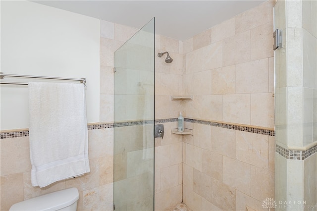 bathroom featuring a shower with door, tile walls, and toilet