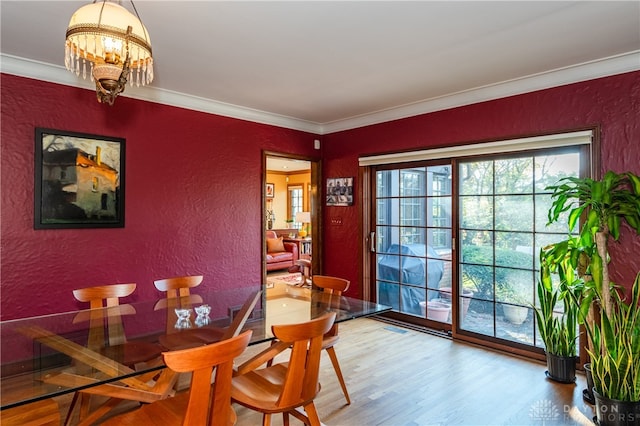 dining area with hardwood / wood-style flooring, a notable chandelier, and crown molding