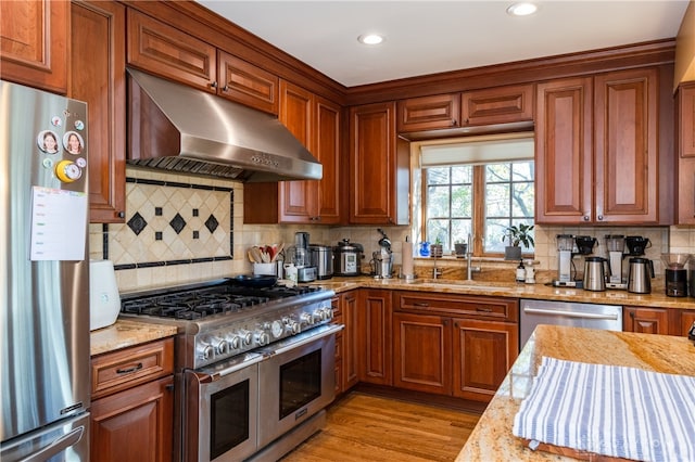 kitchen featuring decorative backsplash, light stone countertops, light hardwood / wood-style flooring, and stainless steel appliances