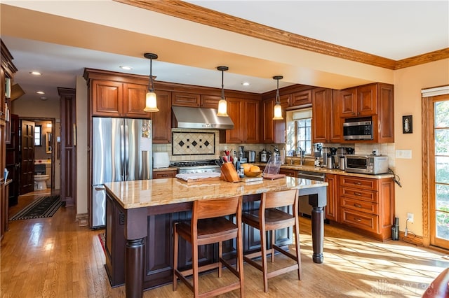 kitchen with plenty of natural light, a kitchen island, stainless steel appliances, and hanging light fixtures