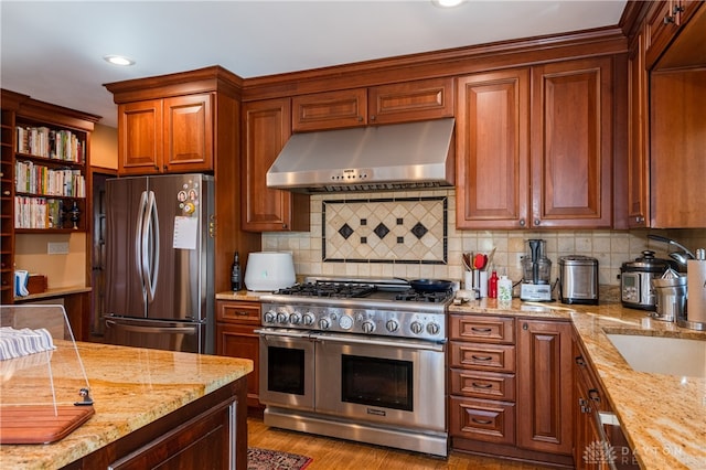 kitchen with light stone counters, stainless steel appliances, tasteful backsplash, and light hardwood / wood-style flooring