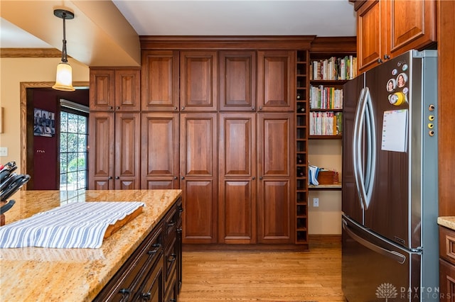 kitchen featuring decorative light fixtures, stainless steel fridge, light stone countertops, and light hardwood / wood-style floors