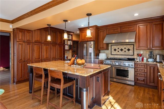 kitchen featuring pendant lighting, dark wood-type flooring, appliances with stainless steel finishes, a kitchen island, and light stone counters