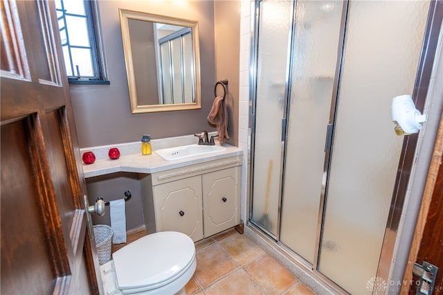 bathroom featuring tile patterned flooring, vanity, toilet, and a shower with shower door